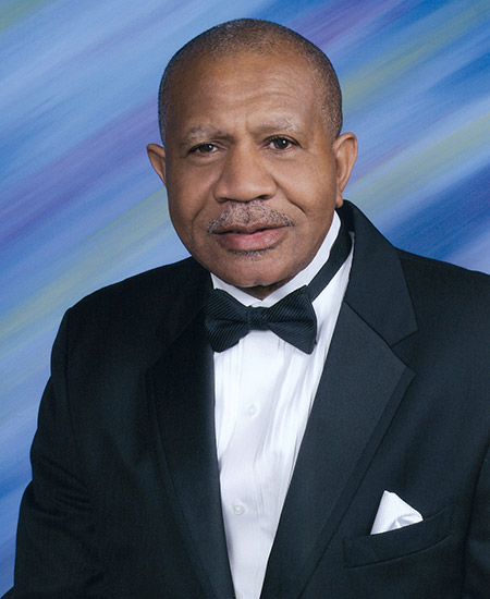African-American man with mustache smiling in tuxedo