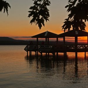 two gazebos over a lake in silhouette at sunset