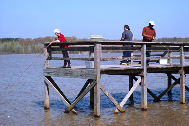 three people fishing off a dock