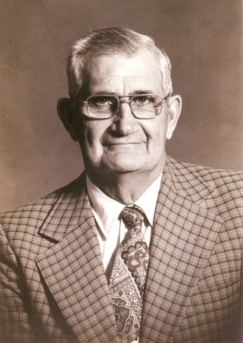 older white man in glasses  wearing checkered suit and tie