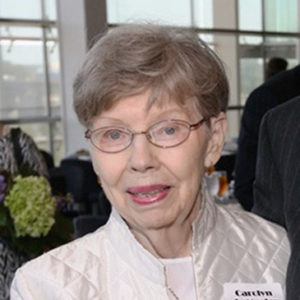 Old white woman with glasses smiling in white jacket