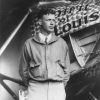 Young white man in suit and jacket standing beside his airplane named the "Spirit of St. Louis"