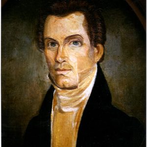 White man in black suit jacket cravat with long neck large eyes short receding brown hair with curls