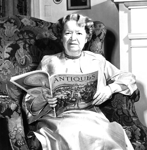 white woman in chair holds magazine "Antiques"