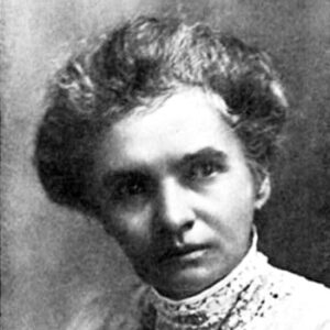 Portrait photo of a serious white woman making a sidelong glance with her hair up wearing a dress with a lace neck and a pendant necklace