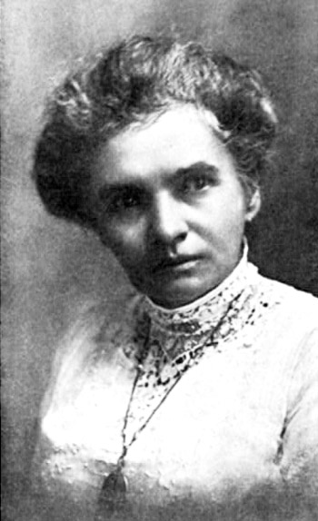 Portrait photo of a serious white woman making a sidelong glance with her hair up wearing a dress with a lace neck and a pendant necklace