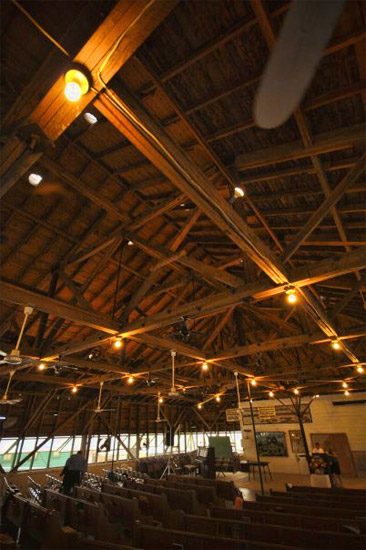 Interior of building with wood trusses and rows of pews