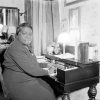 Older African-American woman seated at her desk with reflection in mirror behind her