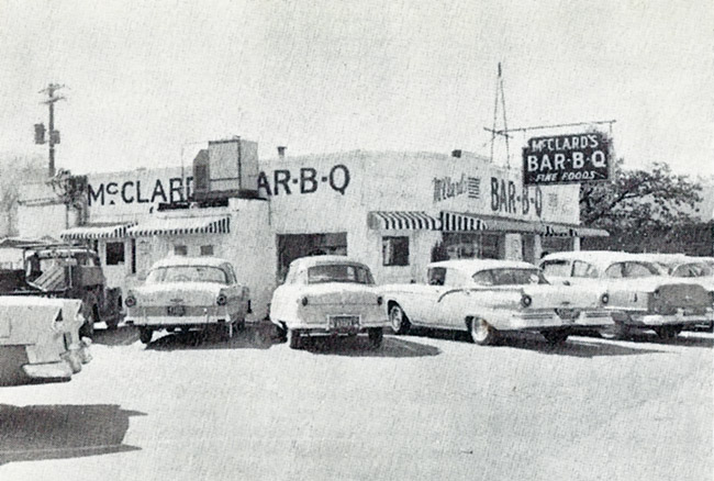 Single-story white restaurant building with sign and cars in parking lot