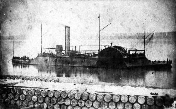 Large iron boat with chimneys flagpoles and sailors viewed across wall of floating barrels.