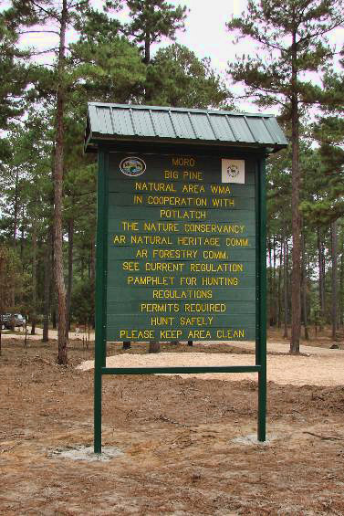 Green park sign with yellow text in wooded area