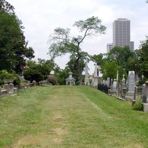 Cemetery path with gravestones, trees, skyscrapers in background