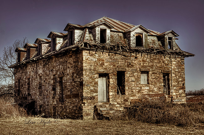 Abandoned two-story brick and stone building in field