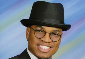 African-American man with glasses in hat and tuxedo