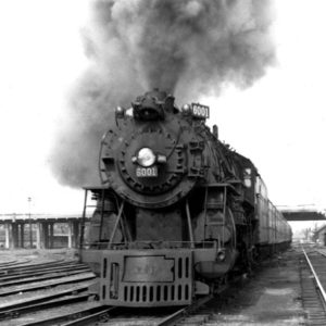 Steam locomotive on tracks with smoke billowing from its boiler