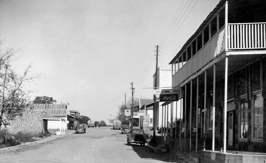 Storefronts and cars on town street with power lines