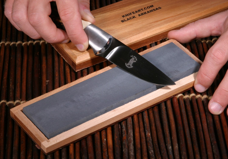 Small knife being sharpened by hand with a stone