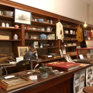Artifacts on table and in wooden shelving on display in exhibit room