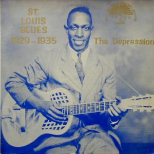 African-American man in suit and tie playing a metal bodied resonator acoustic guitar on album cover with gold text