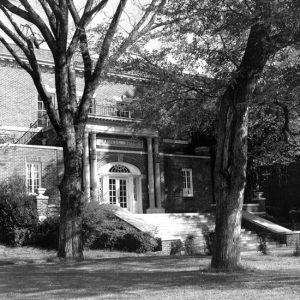 Two-story brick building with arched entrance way and trees