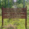 "Pine City Natural Area a bird sanctuary managed by the Arkansas Natural Heritage Commission" sign in forest