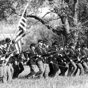 Civil War re-enactor formation in field with rifles, American flag