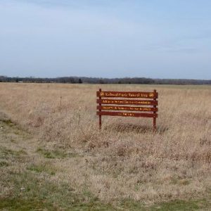 Red wooden sign with yellow text on  prairie