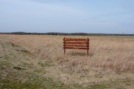 Red wooden sign with yellow text on  prairie