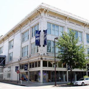 Multistory white building with large windows ornate frieze "the rep" banners
