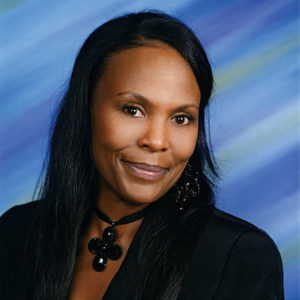 African-American woman smiling in suit and cross necklace