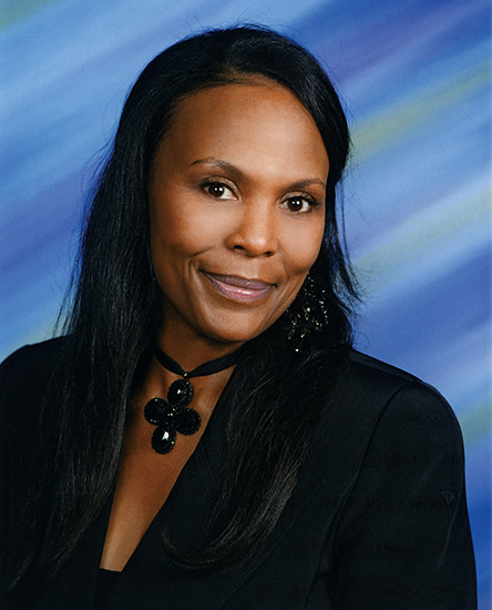 African-American woman smiling in suit and cross necklace