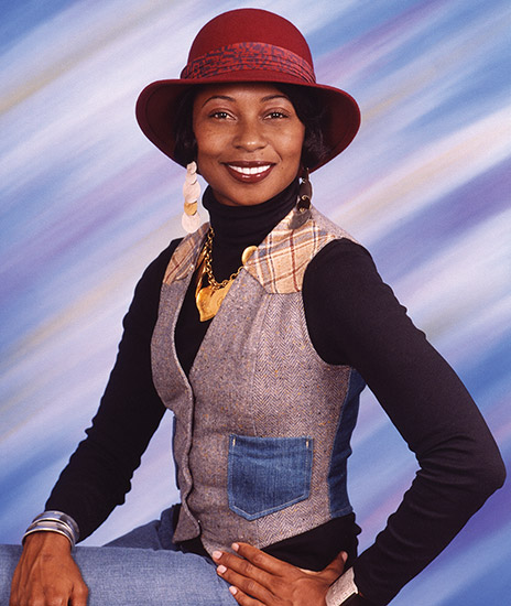Young African-American woman smiling in hat and vest over long sleeve shirt