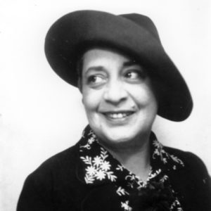Portrait of smiling woman in floral printed blouse, with dark coat and hat