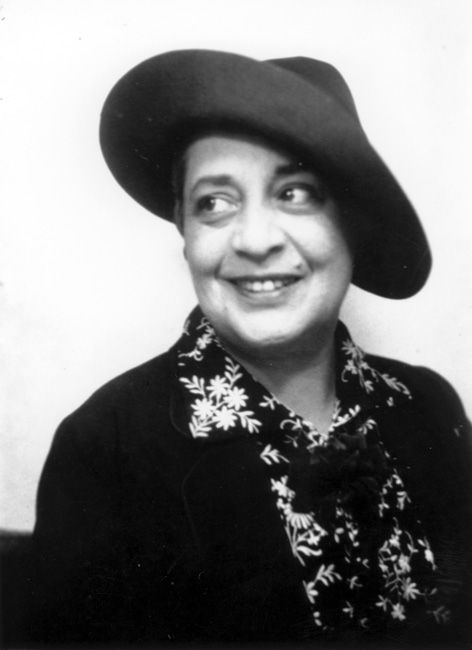 Portrait of smiling woman in floral printed blouse, with dark coat and hat