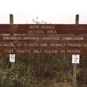 Weathered "Roth Prairie Natural Area Arkansas Natural Heritage Commission" sign on prairie