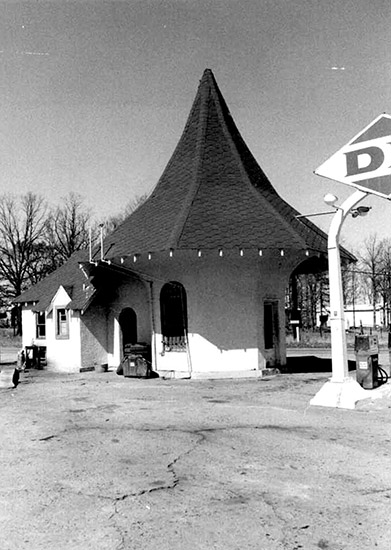 Small gas station with cone shaped roof and sign