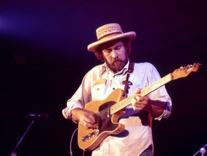 White man with long hair and beard in a hat playing a Fender Telecaster style electric guitar on stage