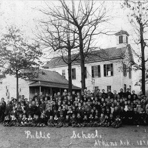 large group of white children and faculty posing together with multistory building with cupola and house in the background