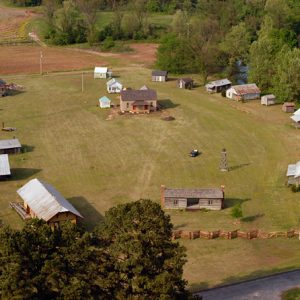 aerial view of small field with several small buildings partially enclosed by fence