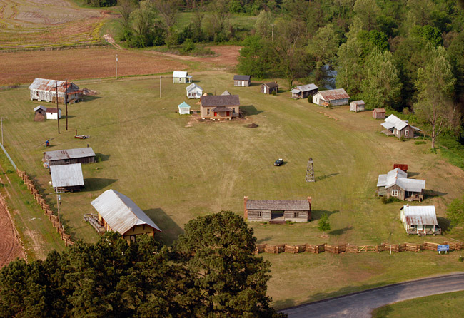aerial view of small field with several small buildings partially enclosed by fence