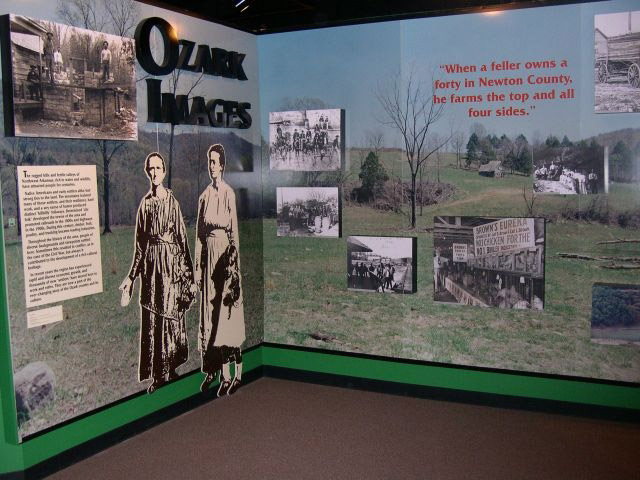 Exhibition display "Ozark Images" with rural background  captions attached photographs and women figures in dresses