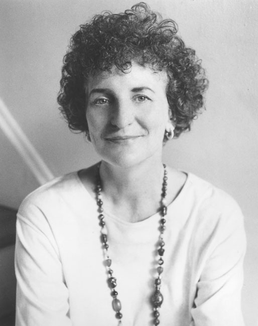 White woman with curly hair wearing beaded necklace