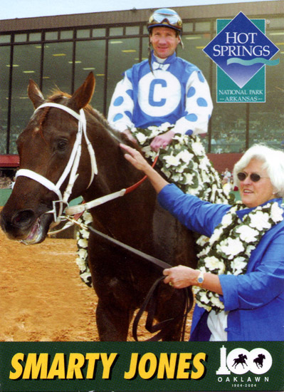 jockey sitting astride horse draped with flowers while woman the lead, with logo in top-right corner reading, "Hot Springs National Park Arkansas," and text at bottom reading, Smarty Jones, Oaklawn"