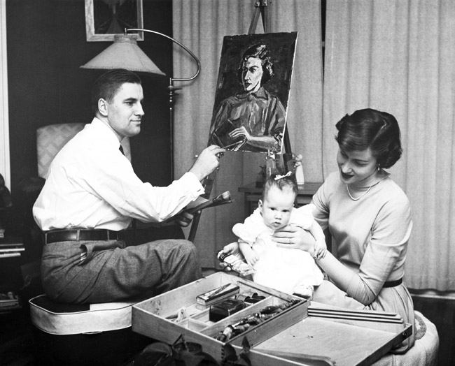 White man painting portrait of white woman as she models sitting holding infant girl