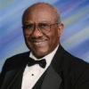 Older African-American man with glasses smiling in tuxedo