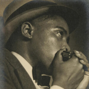 African-American man in suit and hat playing a harmonica