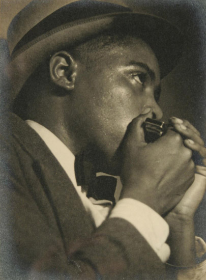 African-American man in suit and hat playing a harmonica