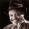 African-American man smiling in hat and suit with saxophone