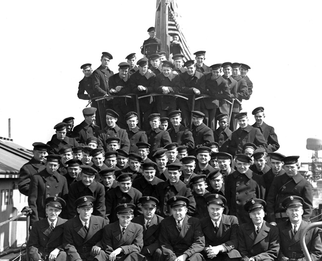 Uniformed Navy group photo atop docked submarine