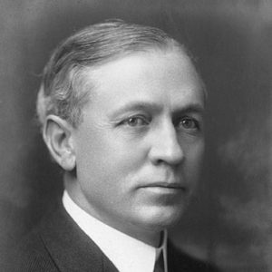 White man with brushed-back hair in suit and tie